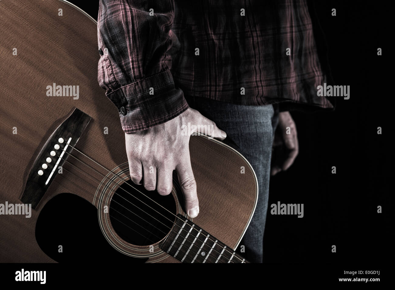 Ein Mann hält eine akustische Gitarre. Stockfoto