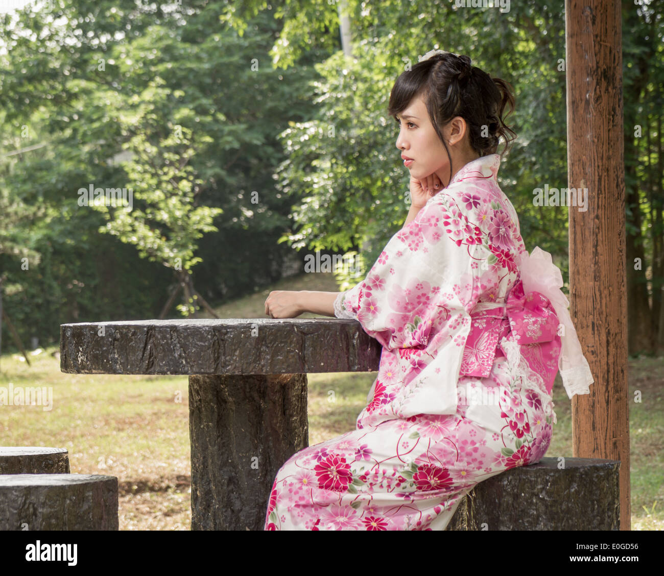 Asiatin in einem Kimono sitzen in einen Garten im japanischen Stil Stockfoto