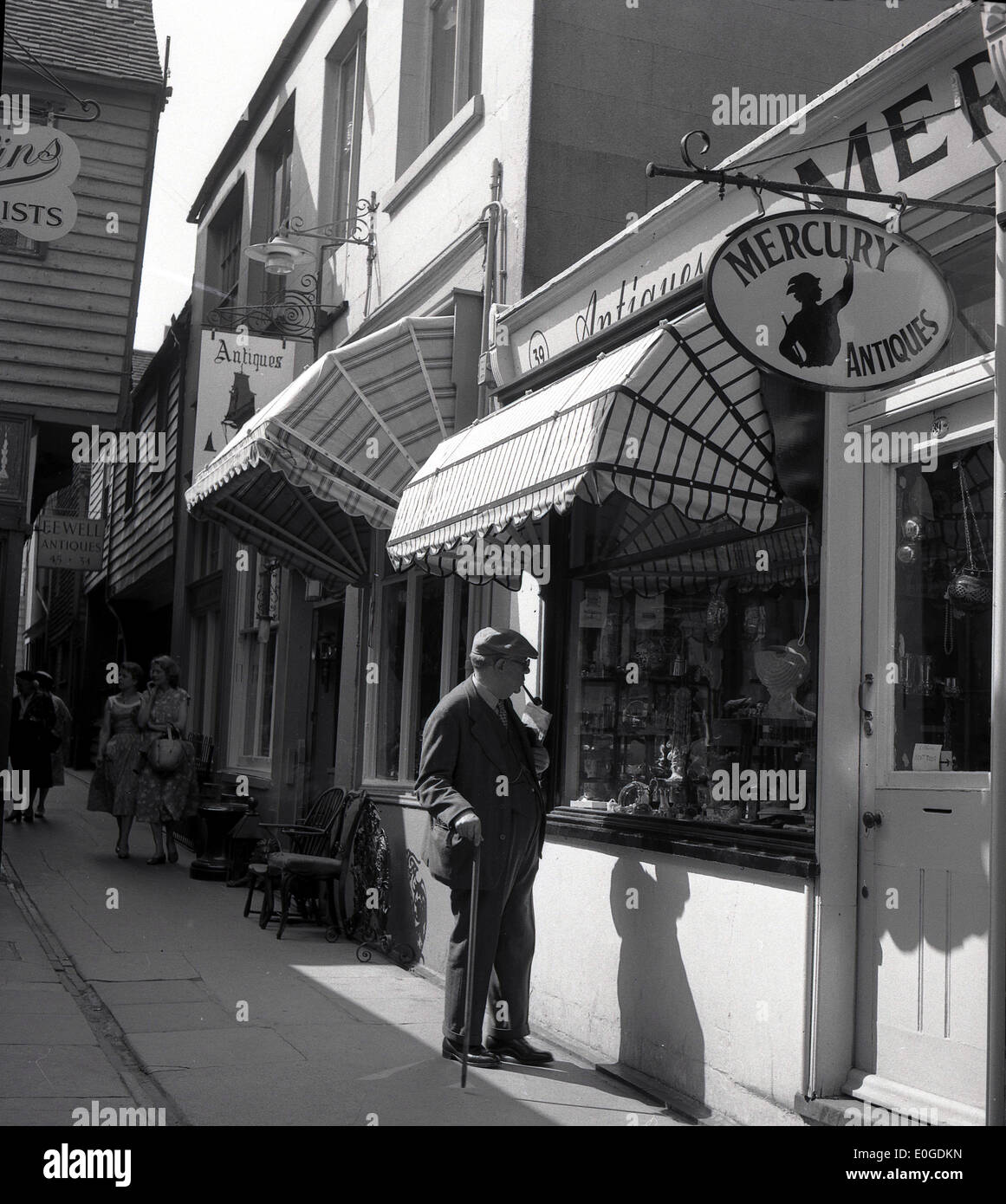 1950er Jahre historische Bild, Seitenstraße, Brighton, ein älterer Mann mit Stock schaut die Schaufenster von Quecksilber Antiquitäten. Stockfoto