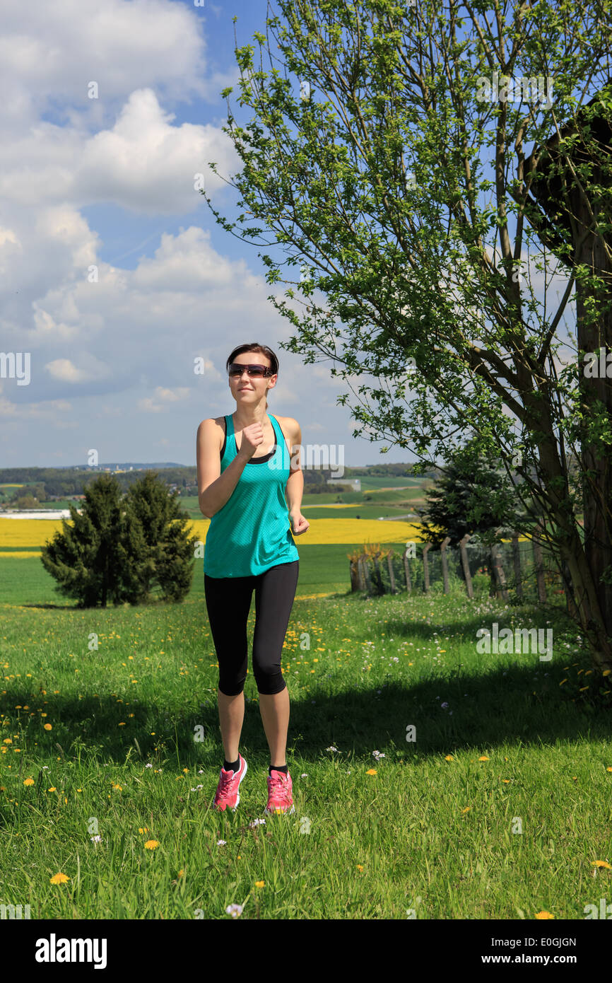 Frau, Joggen durch die Felder im Frühling Stockfoto