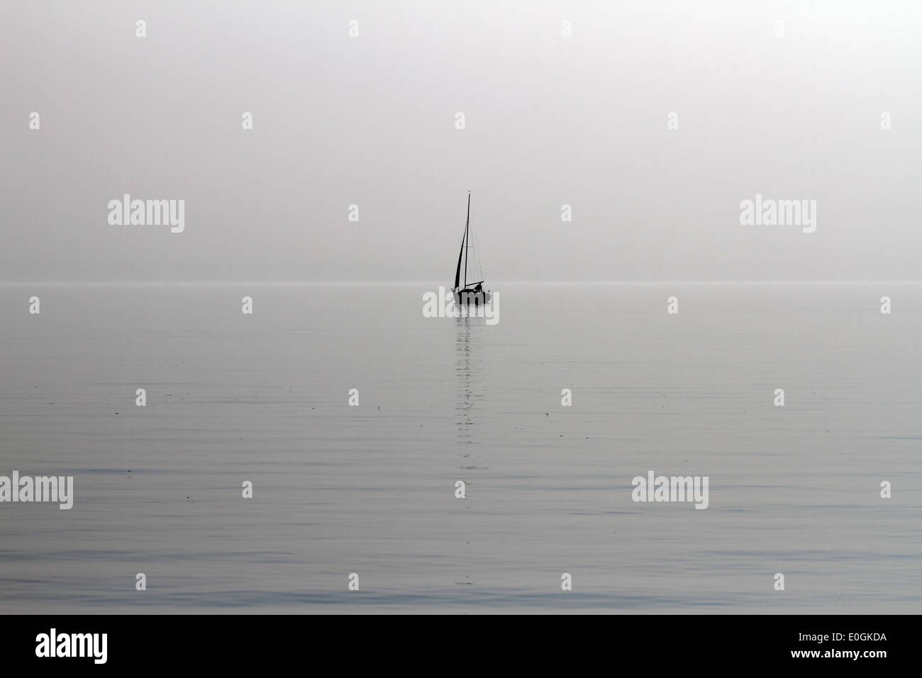 Einsamer Segelboot in einem frühen Frühling See an einem trüben Tag Stockfoto