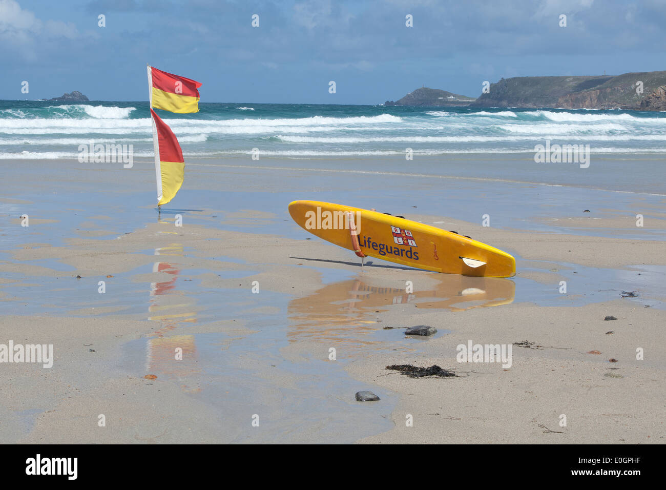 Rettungsschwimmer Surfbrett und Warnflaggen an einem leeren Strand bei Sennen Cove Cornwall Stockfoto