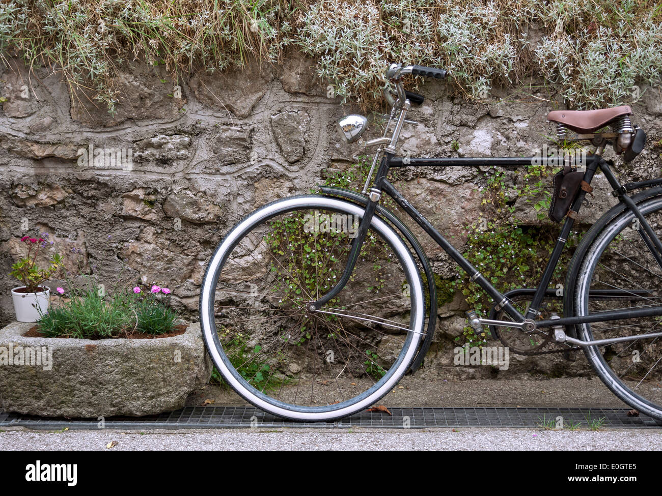 Dekorativer Vintage Fahrrad und Stein Blumentopf gegen Steinmauer Stockfoto