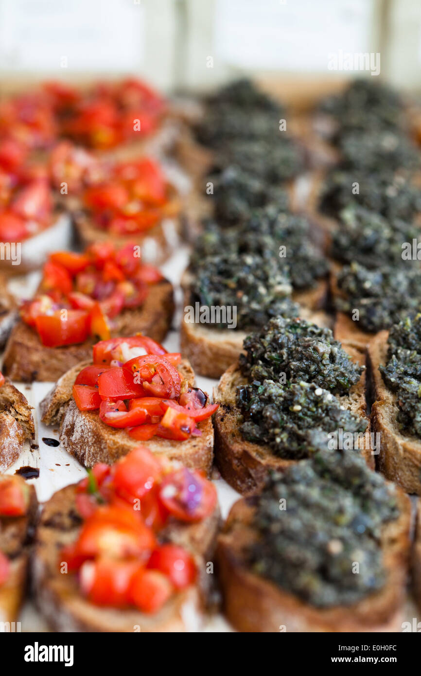 Nahaufnahme von Bruschetta Vorspeisen mit herzhaften Paste und Tomaten Toppings in Zeilen dargestellt Stockfoto