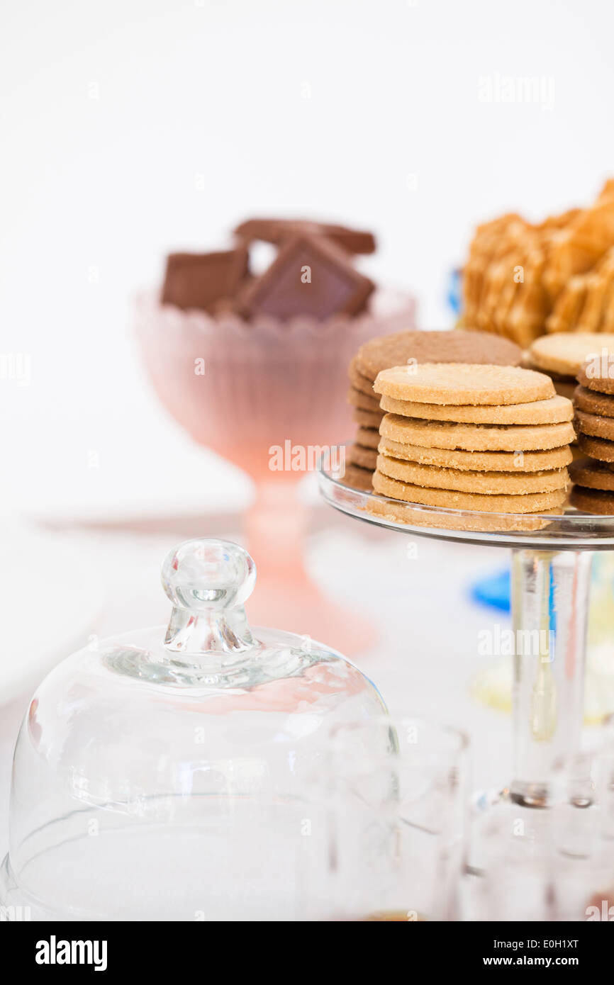 Nahaufnahme der Stapel von Hundekuchen auf Glas servieren Stand mit Schokoladenstückchen und Waffel Kekse in Schalen im Hintergrund Stockfoto