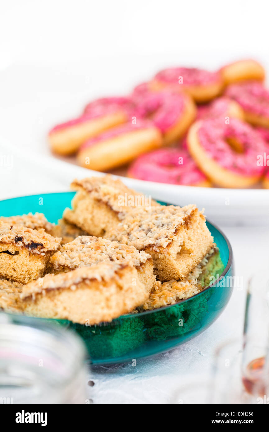 Nahaufnahme der Scheiben von trockenen Kuchen im Glas Servierschale mit rosa farbigen Donuts in Schüssel im Hintergrund Stockfoto