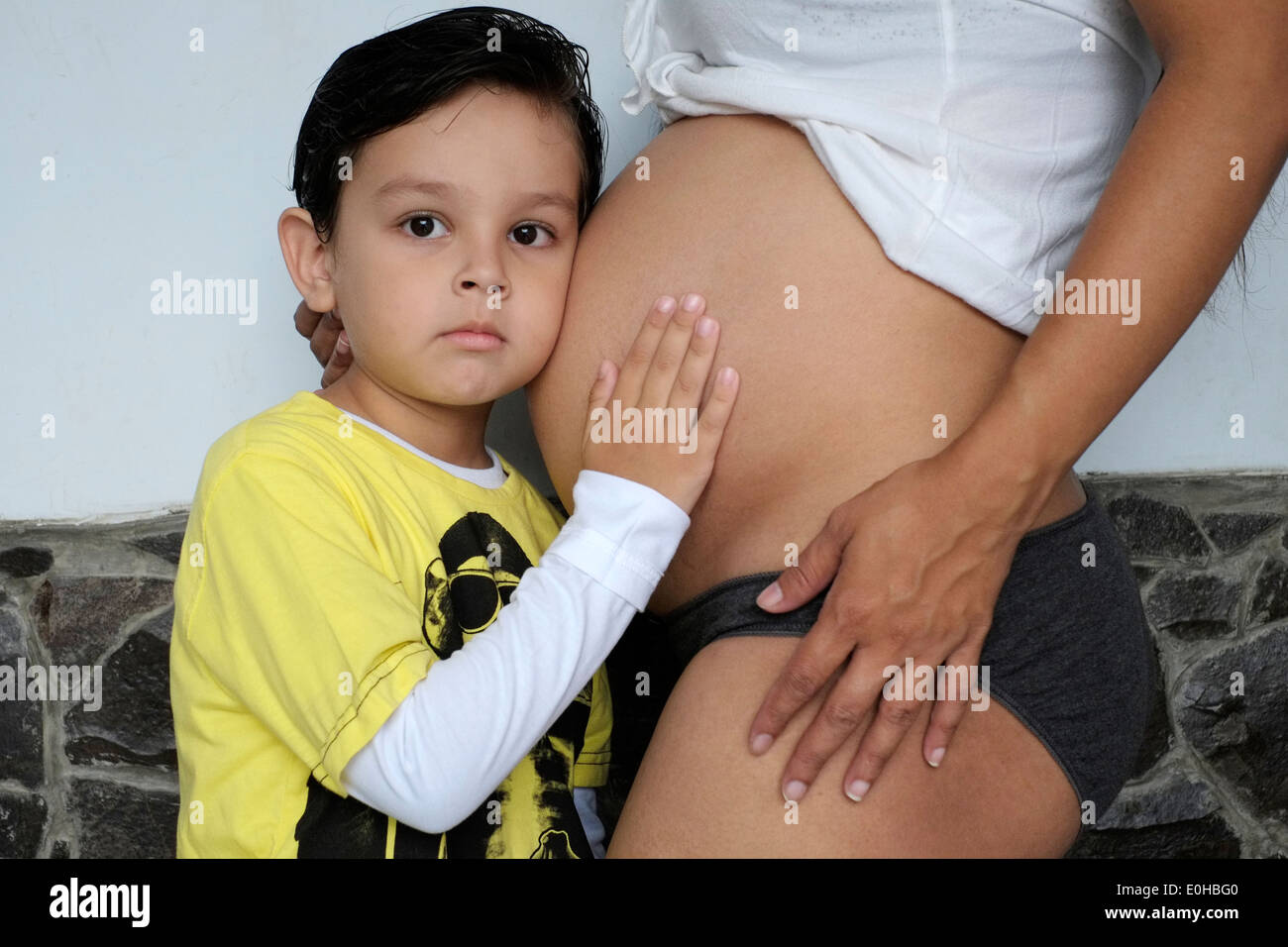 Junge mit Hand auf Mütter schwanger Bauch hören und das Gefühl für die Bewegung des Babys Stockfoto