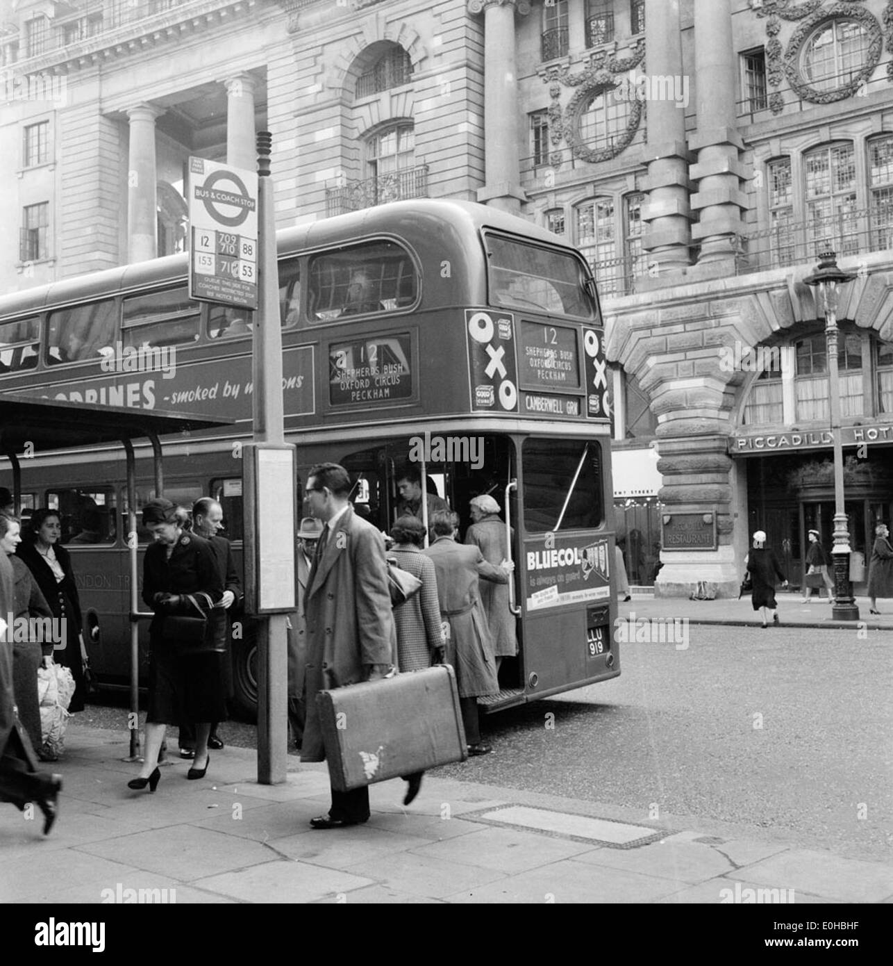 Ein Foto von 1956 einer Bushaltestelle in London mit einem Gebäude von Alexander Stephen & Sons. Das Bild zeigt die öffentliche Verkehrsinfrastruktur in London Mitte des 20. Jahrhunderts während dieser Zeit. Stockfoto