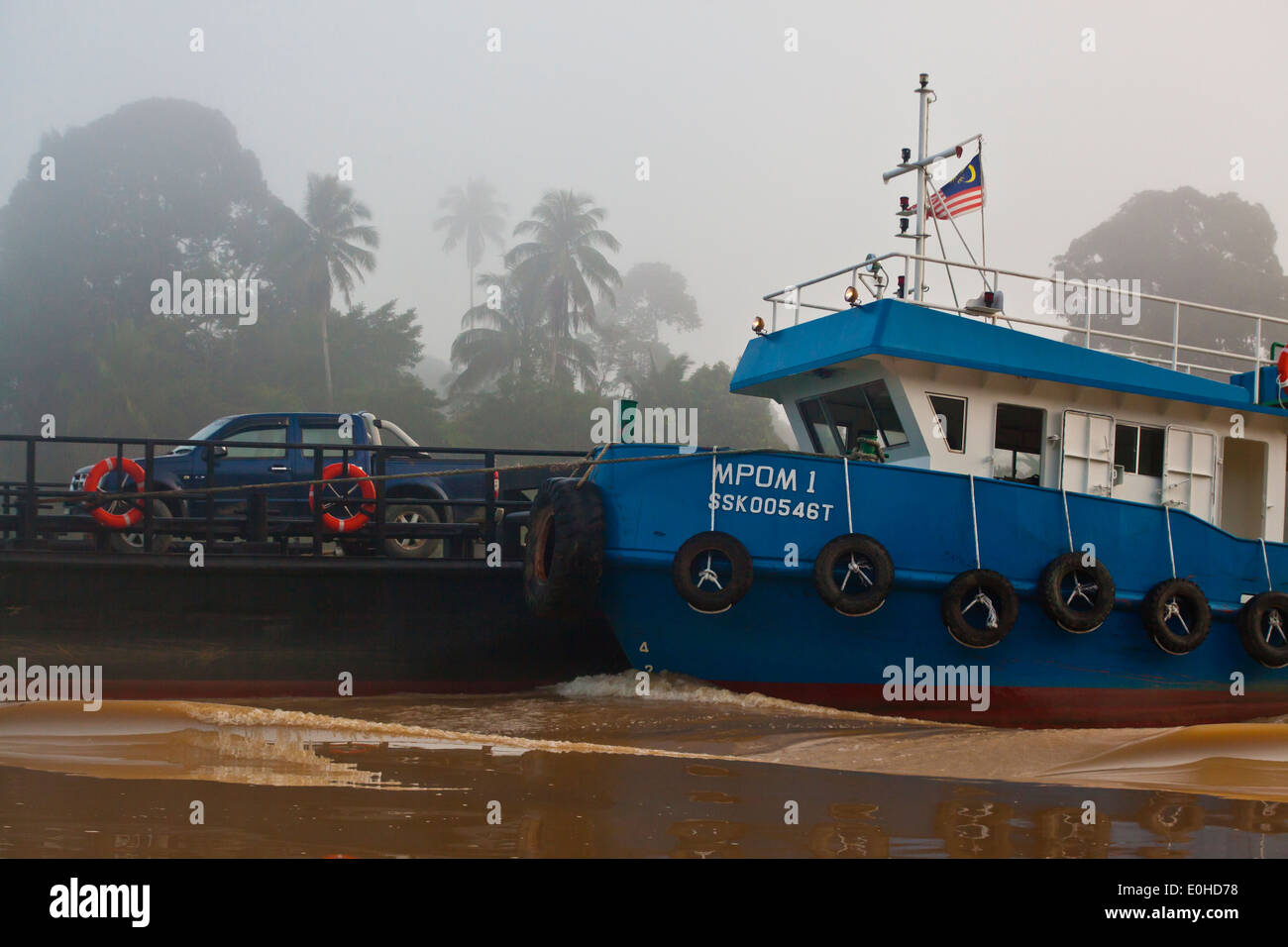 Ein Schlepper treibt ein Schiff für den transport von Autos über den Fluss in der KINABATANGAN RIVER WILDLIFE SANCTUARY - SABAH, BORNEO Stockfoto