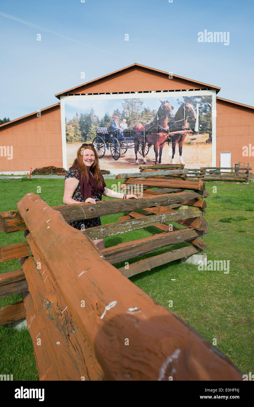 Junge Frau am Hobby Farm Zaun, Coombs, British Columbia, Kanada Stockfoto