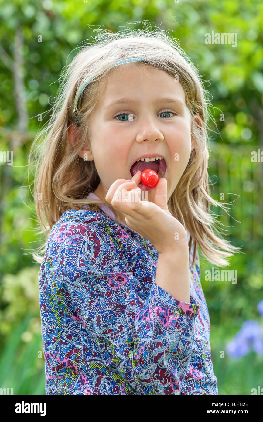 Kleines Mädchen mit Kirsche im Mund Stockfoto
