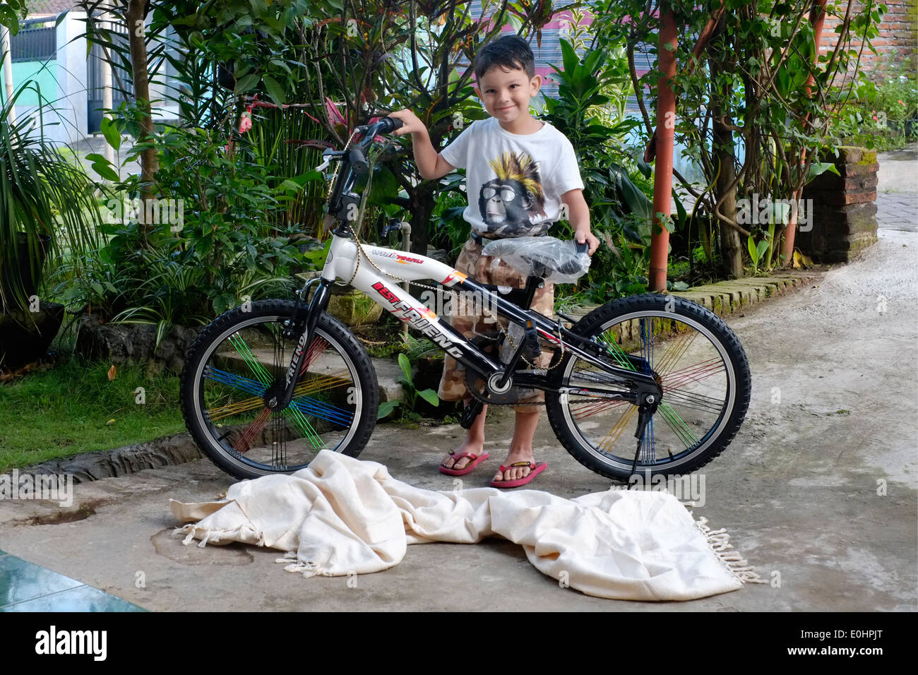 kleiner Junge überglücklich mit dem Überraschungs-Geschenk von seinem ersten Fahrrad in seinem Dorf Haus in Ost-Java-Indonesien Stockfoto