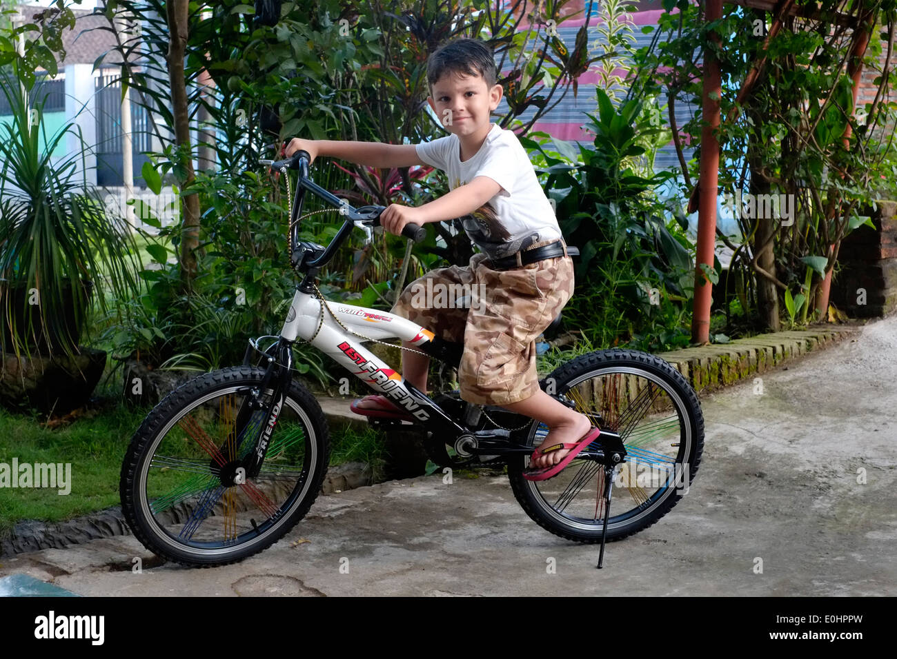 kleiner Junge überglücklich mit dem Überraschungs-Geschenk von seinem ersten Fahrrad in seinem Dorf Haus in Ost-Java-Indonesien Stockfoto