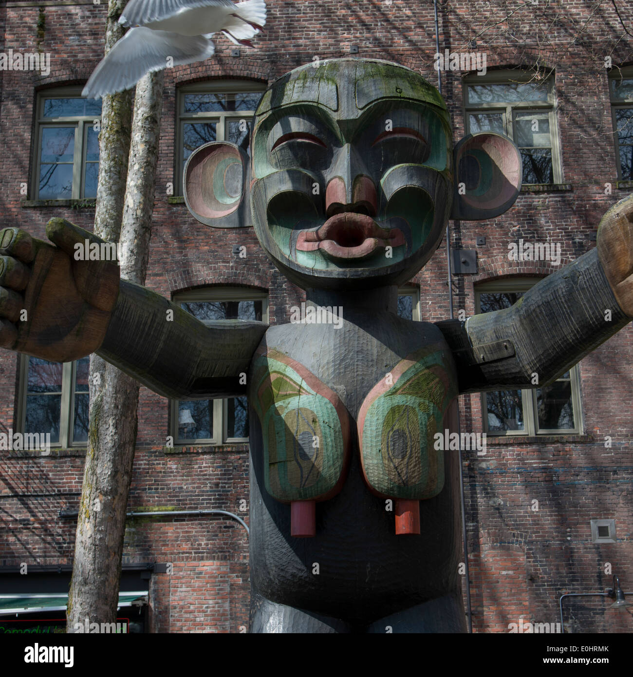 Totempfahl vor einem Gebäude, Occidental Park, Pioneer Square, Seattle, Washington State, USA Stockfoto