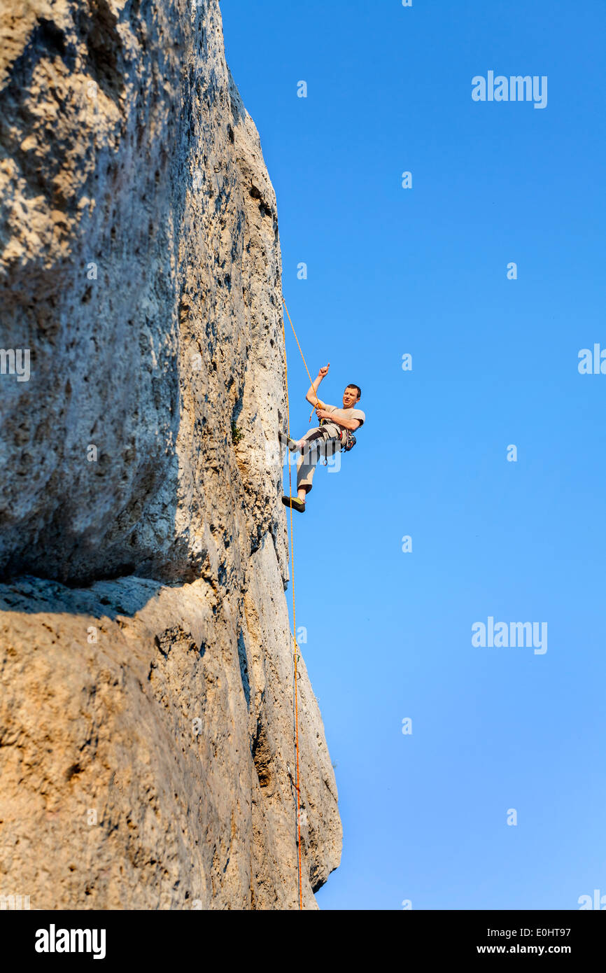 Extreme Klettern, Mann auf natürliche Mauer mit blauem Himmel. Stockfoto