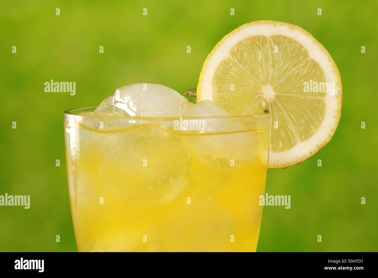 Limonade in ein Glas mit Eiswürfeln, serviert mit einer Zitrone, reichlich Exemplar Stockfoto