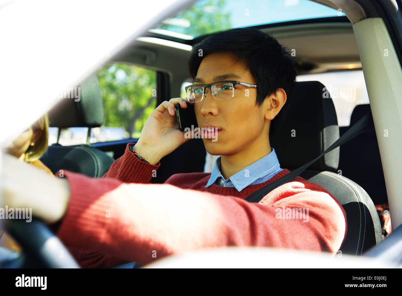 Junge asiatische Mann Auto fahren und telefonieren mit Handy Stockfoto