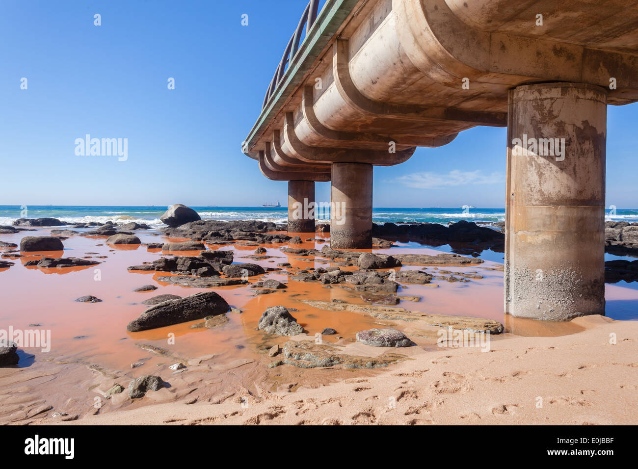Verschmutzung, die Brauchwasser Flüssigkeit gießt in Strand Felsen und blauem Meer abfallender Küste. Stockfoto