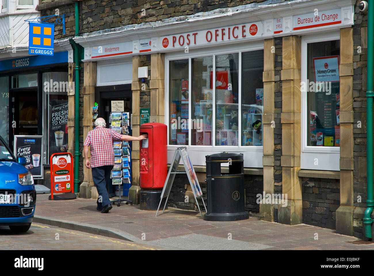 Mann Entsendung einen Brief im Briefkasten außerhalb Postamt, Cumbria, England UK Stockfoto
