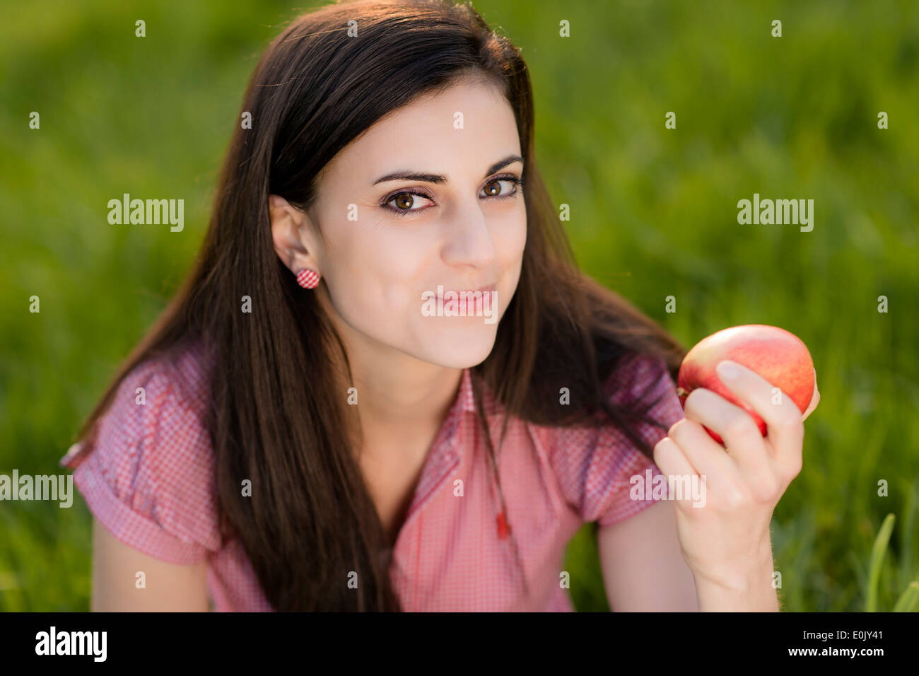 Frau mit Apfel auf Wiese, (Model Release) Stockfoto