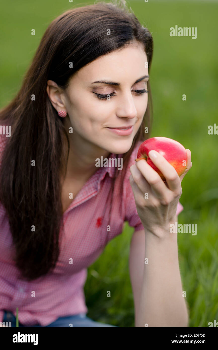 Frau mit Apfel auf Wiese, (Model Release) Stockfoto