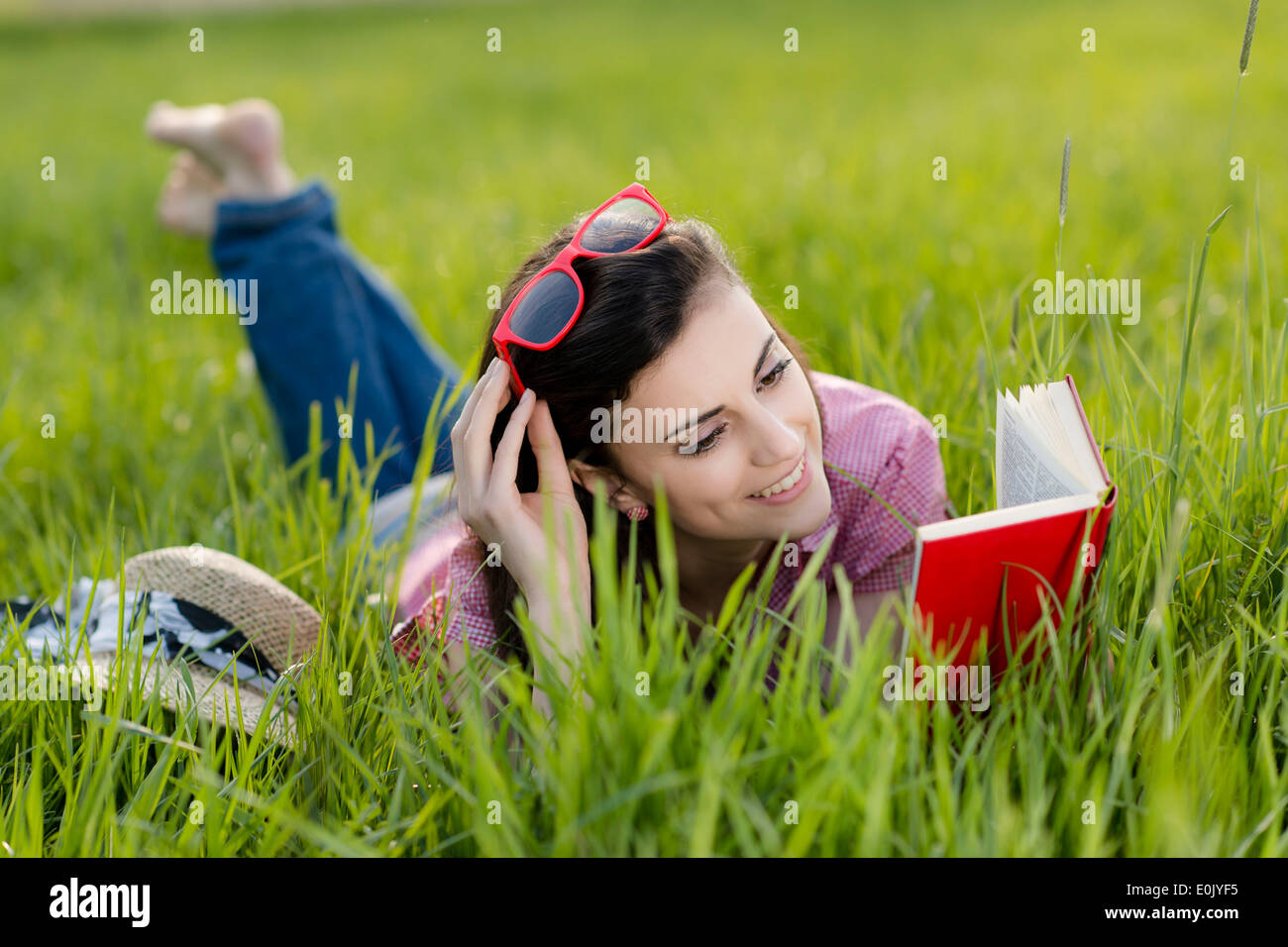 Frau liegend mit Buch auf Wiese, (Model Release) Stockfoto
