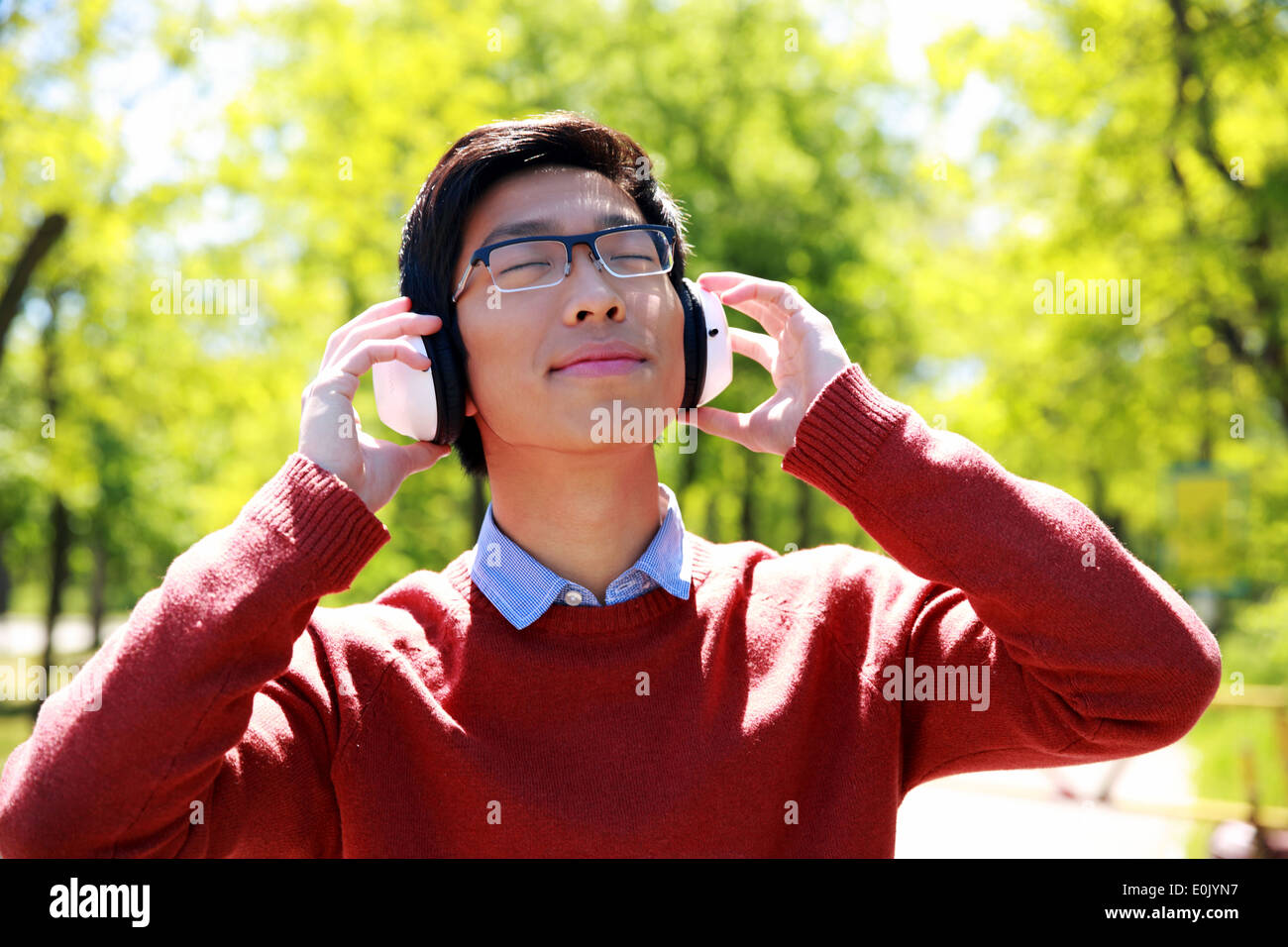 Junge asiatische Mann anhören von Musik im park Stockfoto