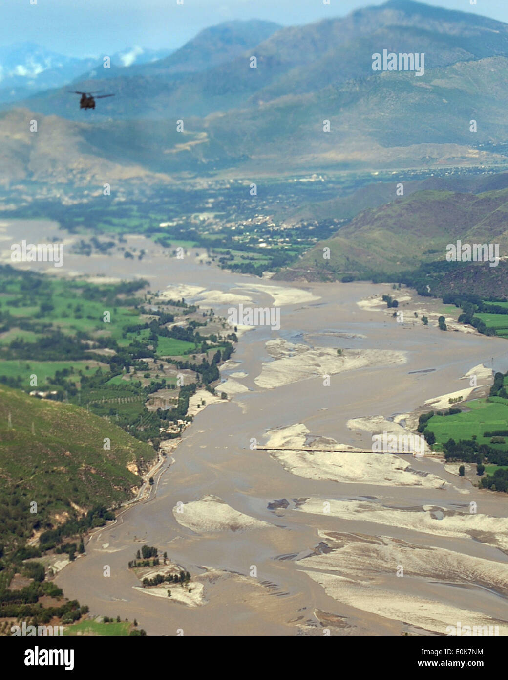 Ein Chinook in Unternehmen B, Task Force Raptor, 3. Combat Aviation Brigade, TF Falcon fliegt über eine Brücke durch Hochwasser zerstört Stockfoto