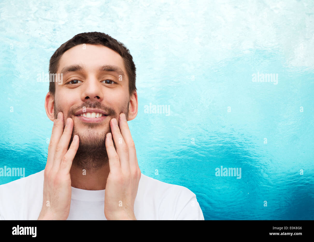 schöne lächelnder Mann sein Gesicht berühren Stockfoto
