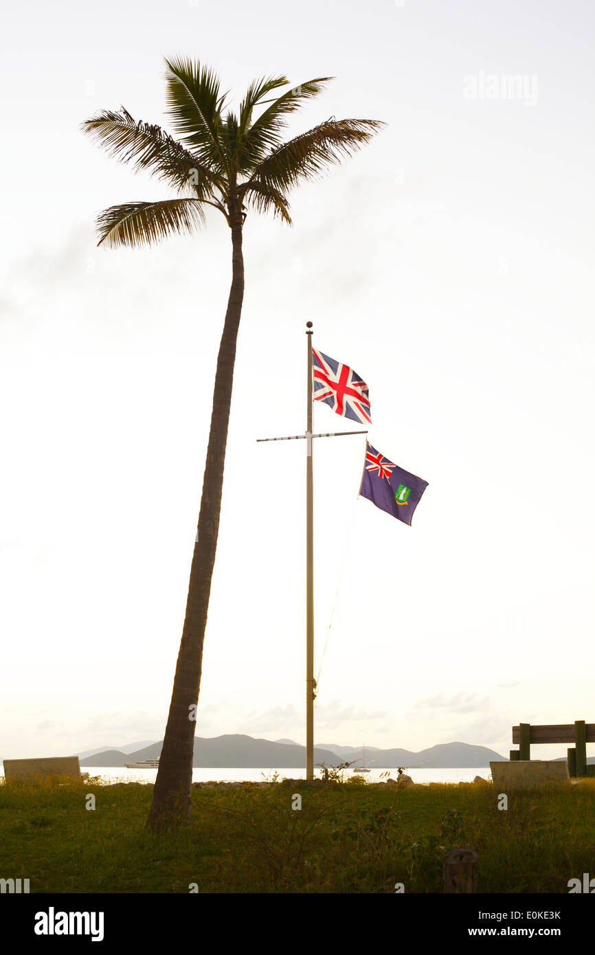 Eine britische Flagge fliegt neben einer Palme Silhouette gegen den Sonnenuntergang in den British Virgin Islands. Stockfoto