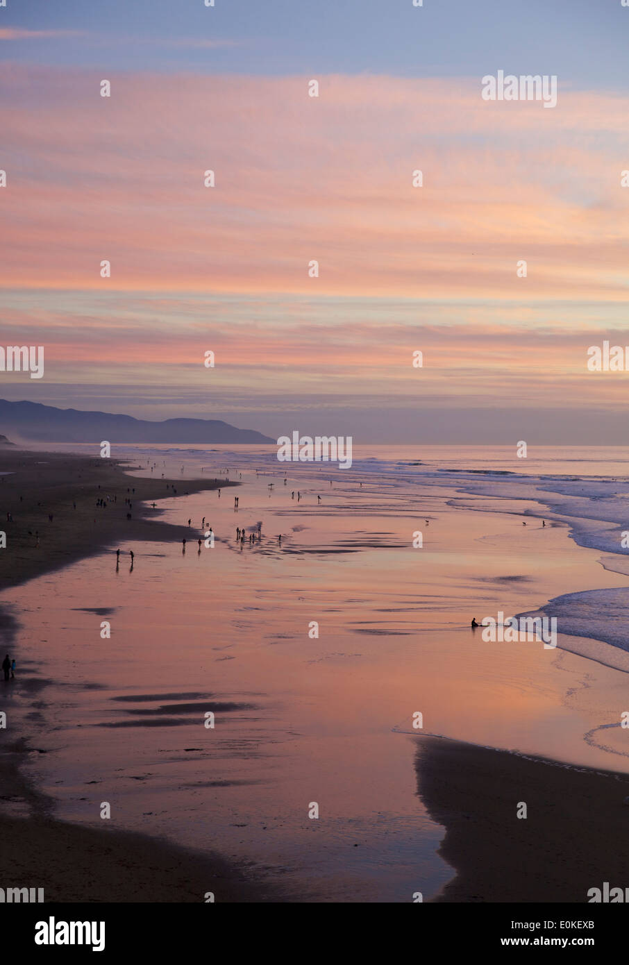 Menschen zu Fuß entlang der Küste sind gegen einen genialen Sonnenuntergang mit Farben blau, rosa und lila und Orange Silhouette. Stockfoto