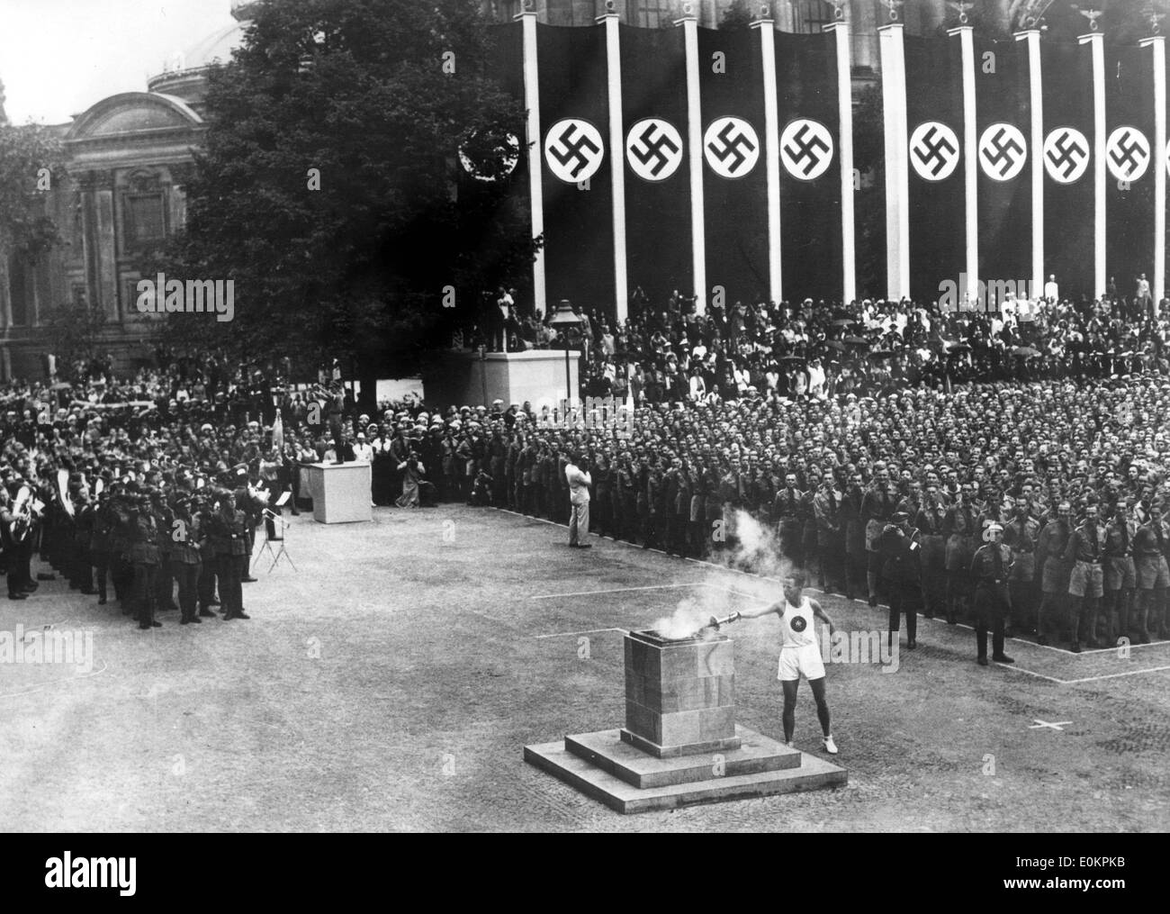 Ein deutscher Leichtathlet Beleuchtung die Fackel bei der Eröffnungsfeier der Olympischen Spiele 1936 in Berlin. Stockfoto
