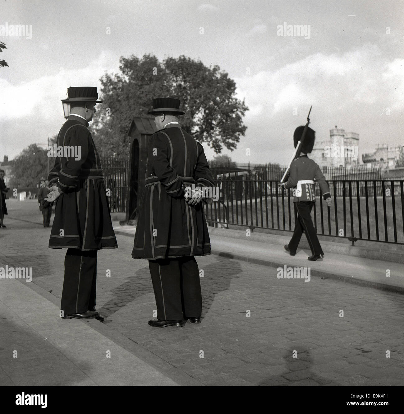 der 1950er Jahre Geschichtsbild von zwei Yeoman, Tower of London, Sentry wachen und ein weiteres Königinnenwache marschieren in den Hintergrund. Stockfoto