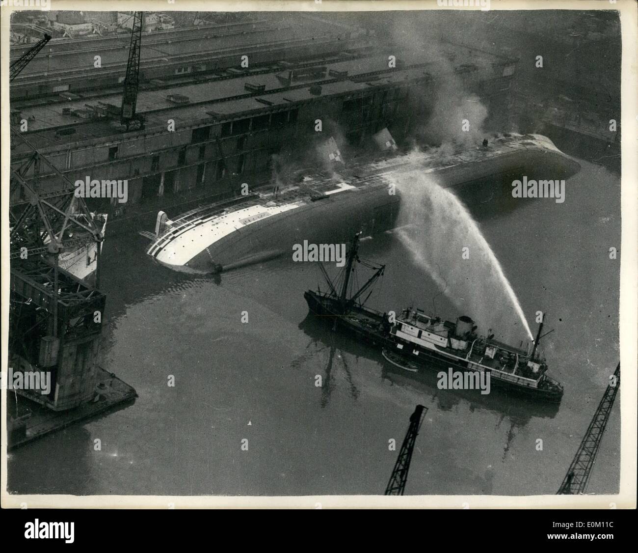 1. Januar 1953 - Liner noch brennend: Rauch bauschte noch von der Hälfte eingetaucht, Burn-out Liner Empress of Canada, wie sie auf ihrer Seite im Gladstone Dock, Liverpool, heute Nachmittag lag. Etwa 20 Feuerwehrleute waren an Bord, und wie in diesem Luftbild zu sehen, spielten die mächtigen Wasserstrahlen ein Löschboot gegen den Liner Rumpf, an der Stelle, wo das Heizöl gelagert wurde, um die Panzer zu kühlen. Stockfoto