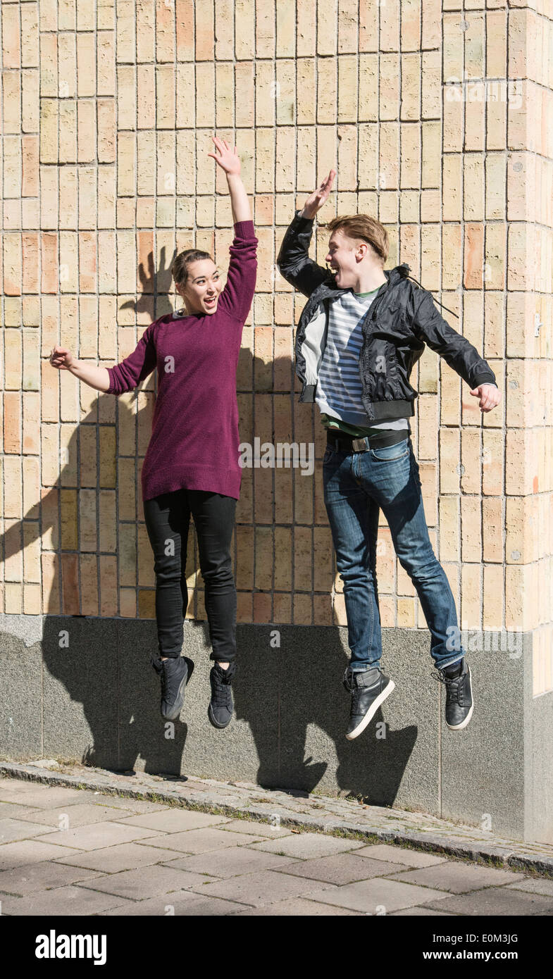 Junger Mann und Frau springen und dabei einen hohen fünf Gruß Stockfoto