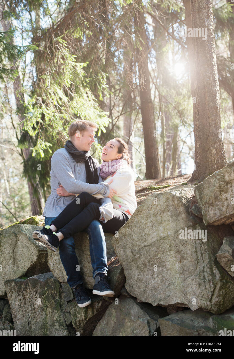 Junges Paar in der Natur auf den großen Felsen in Wäldern während einer Wanderung ausruhen. Sitzt auf der Kante halten sie einander. Stockfoto