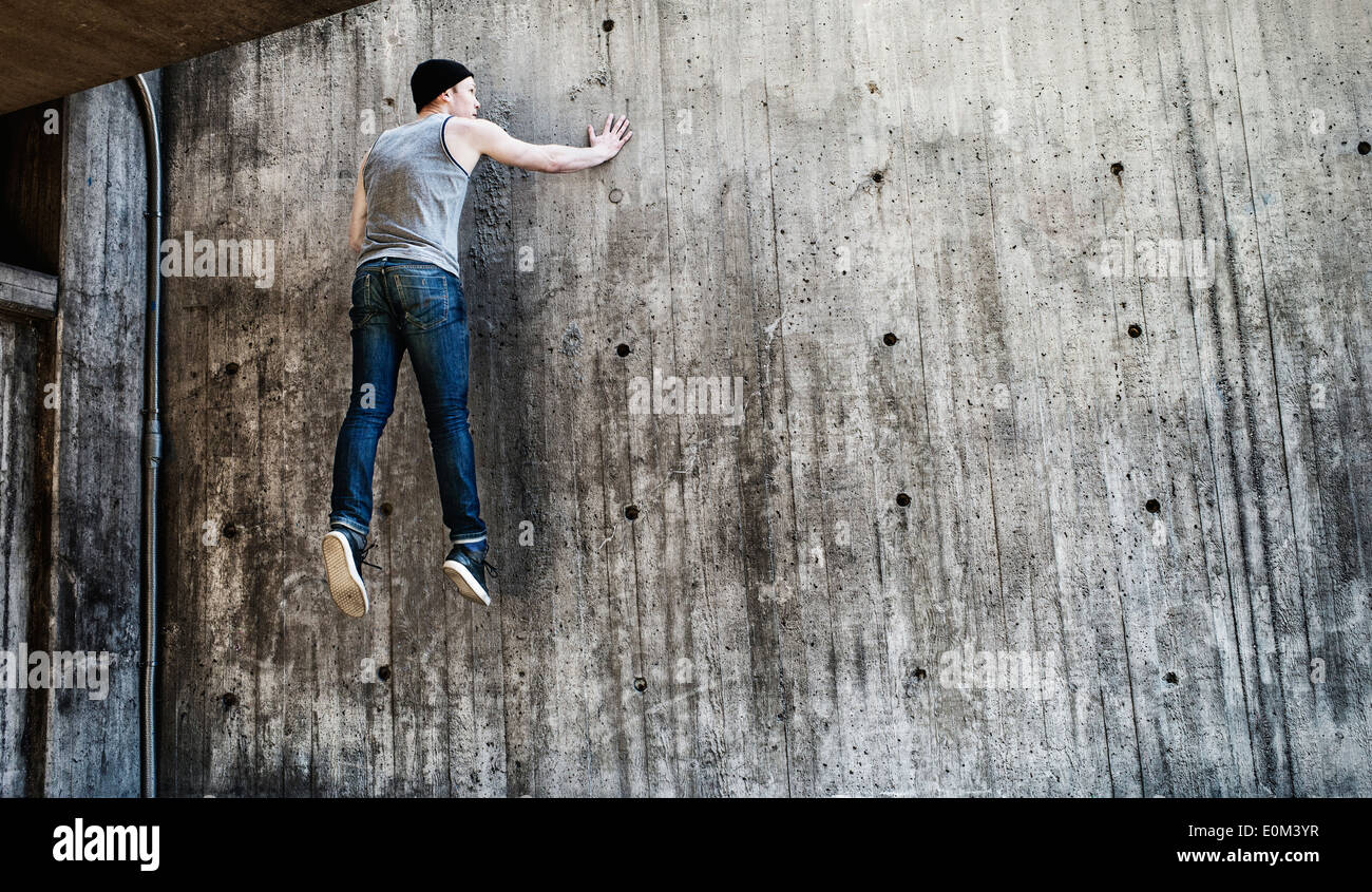 Junger Mann springt in einen Parkour bewegen auf Betonwand urbanen Szene mit Lebensstil Moment der Jugend voller Energie und Kraft Stockfoto