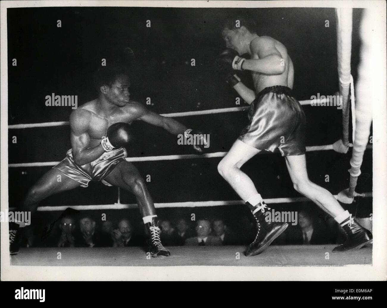 10. Oktober 1953 - McCarthy verliert endlich geschlagen von nigerianischen am Royal Albert Hall.: lächelnd Sammy McCarthy, Anwärter für den britischen Titel im Federgewicht, gewählt hatte seine ungeschlagen Zertifikat seine letzte Nacht in der Royal Albert Hall auf fuzzy-behaarte nigerianischen Hogan Bassy entnommen. Foto zeigt Bassey kauert niedriger als McCarthy in eilte, um anzugreifen. Stockfoto