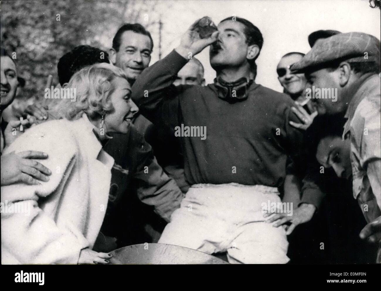 2. Februar 1955 - Jean Behra gewinnt in PAU: Französische Rennfahrer Jean Behra nimmt ein erfrischendes trinken nach dem Sieg beim grand-Prix-Rennens in PAU. Auf verließ seine Frau, die an Mannes Sieg glücklich scheint. Stockfoto