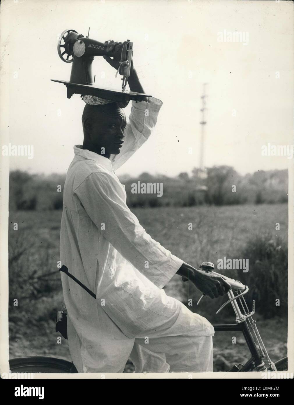 27. Januar 1956 - geht es auf dem Kopf... Schneider - In Nigeria Reisen... Dieser Mann verdient seinen Lebensunterhalt als Schneider in Nigeria - Szene von HM The Queen bevorstehenden Besuch - aber im Gegensatz zu anderen Ländern - dieser Mann geht zu seiner Kunden - und nimmt seine Nähmaschine mit... auf den Kopf. Stockfoto