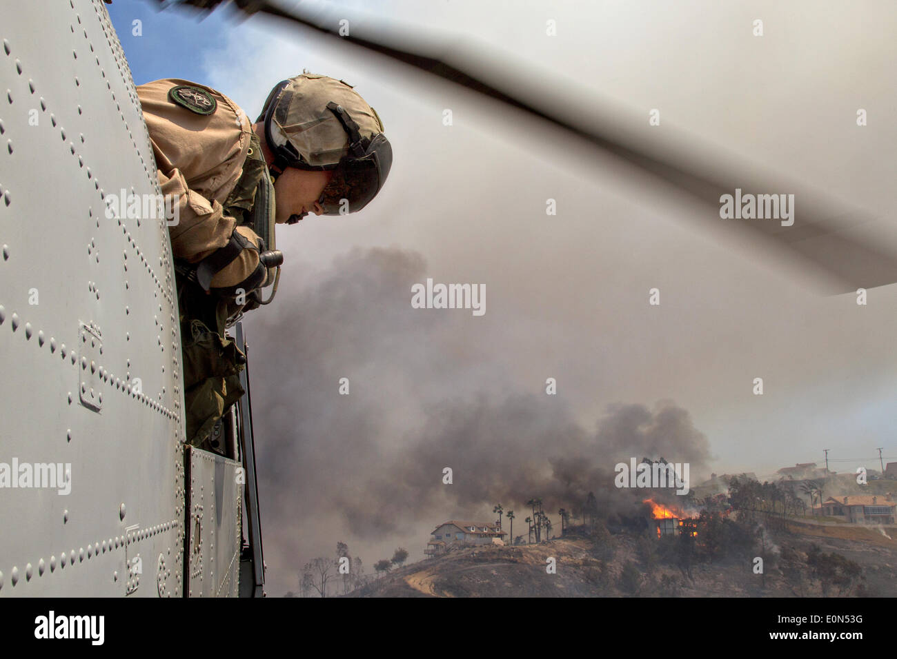 Ein US-Marine blickt aus dem CH-46 Sea Knight Helikopter Unterstützung im Kampf gegen das Cocos Wildfire, wie es brennt die Ausläufern nach Hause 15. Mai 2014 rund um San Marcos, Kalifornien zu zerstören.  Evakuierungen gezwungen mehr als 13.000 Menschen aus ihren Häusern, als das Feuer brannte über San Diego County. Stockfoto