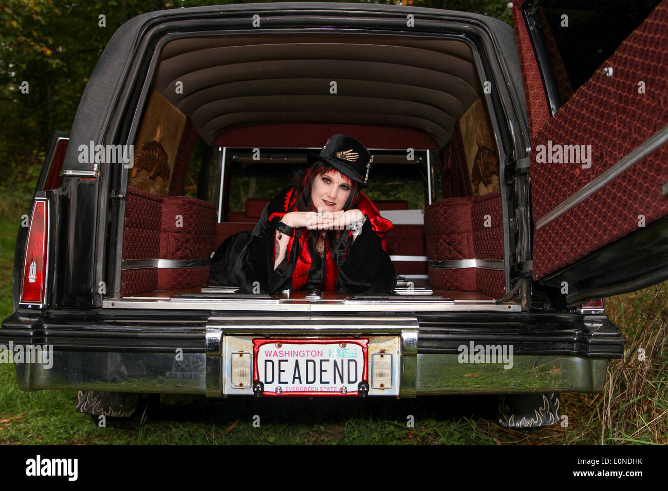 Eine Frau, gekleidet in Gothic Kleidung, blickt von der Rückseite des einen Leichenwagen Stockfoto