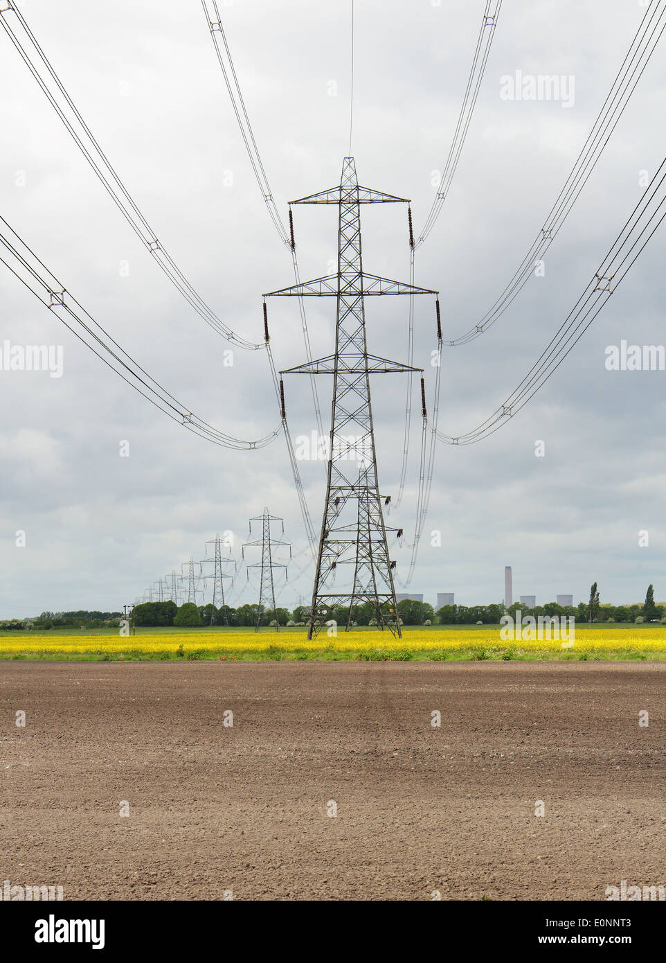 Eine englische Landschaft mit Elektrizität Masten mit Kraftwerk in der Ferne und Bereich der gelben Raps Stockfoto