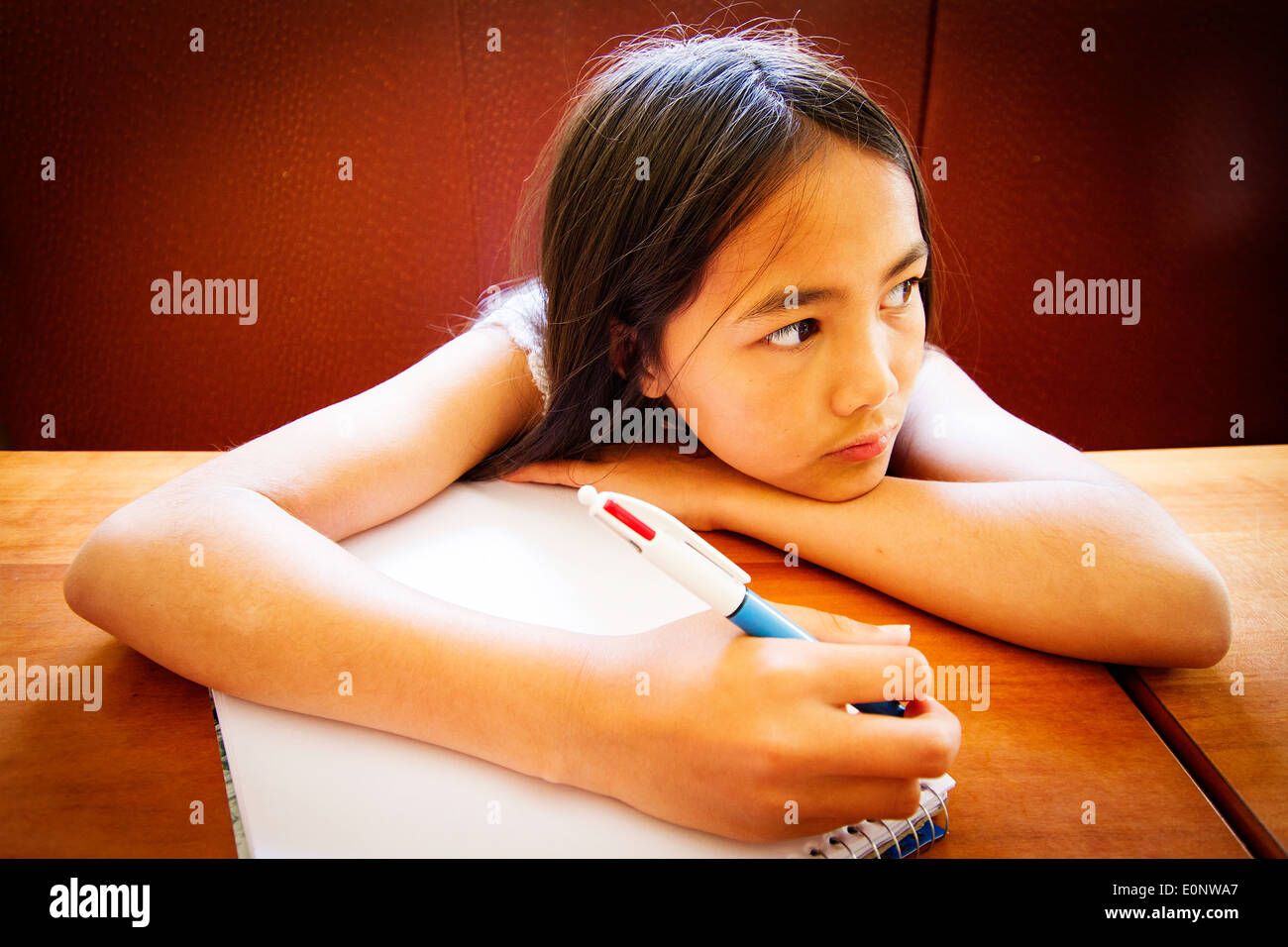 Junge Englisch / Thai Mischlinge Mädchen zeichnen mit einem Stift in einem Malbuch an einem Tisch in einem restaurant Stockfoto