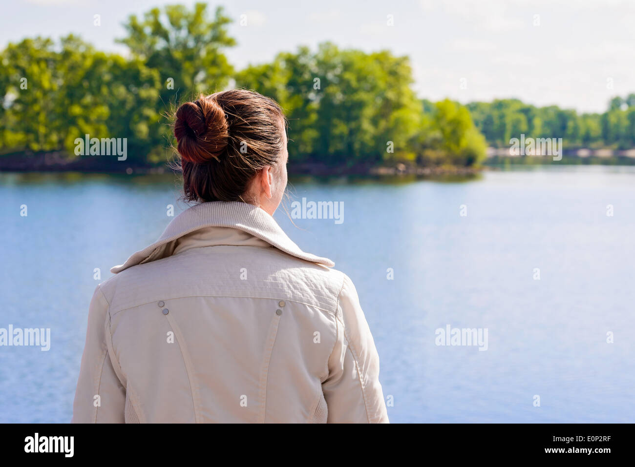 Eine Frau mit einem Blick auf den Fluss in einem schönen sonnigen Frühlingsmorgen chignon Stockfoto