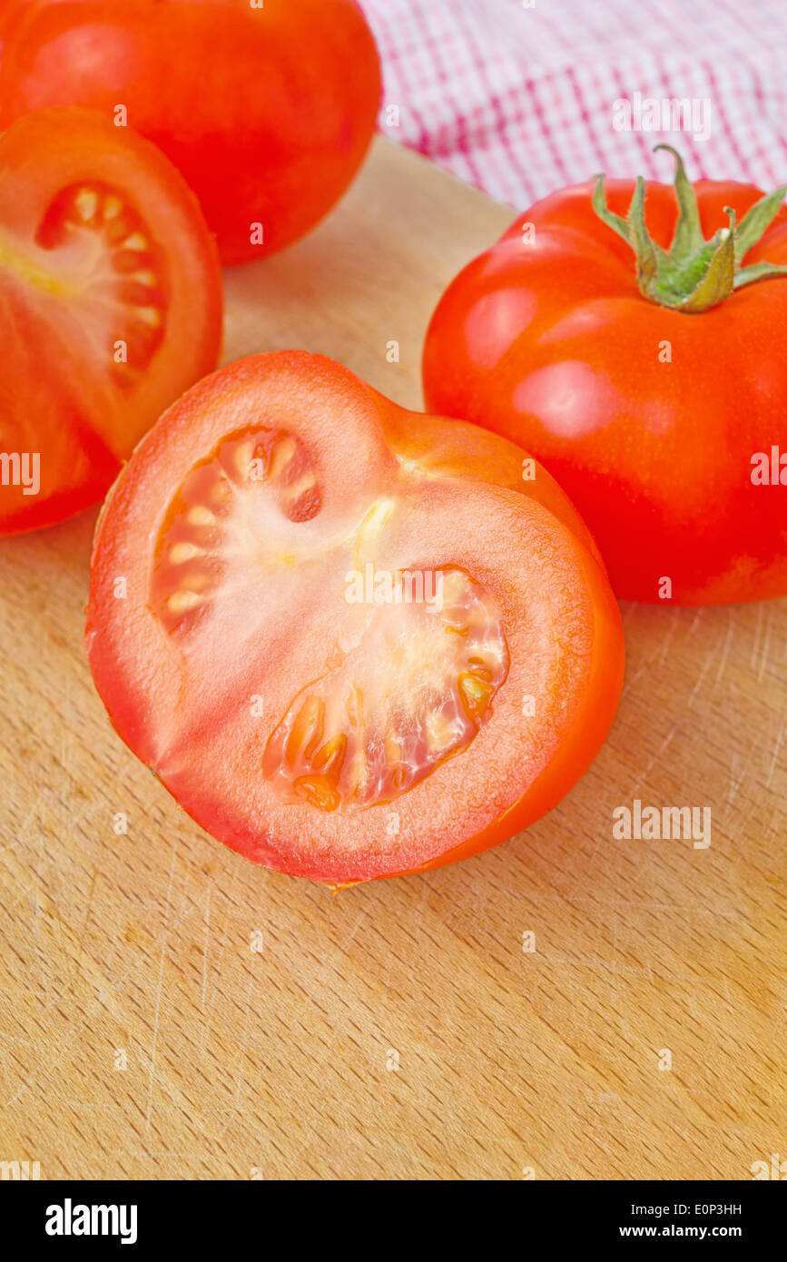 Frische reife Tomaten mit Hälften auf Holztisch, leckere Bio-Gemüse für eine gesunde Ernährung. Stockfoto