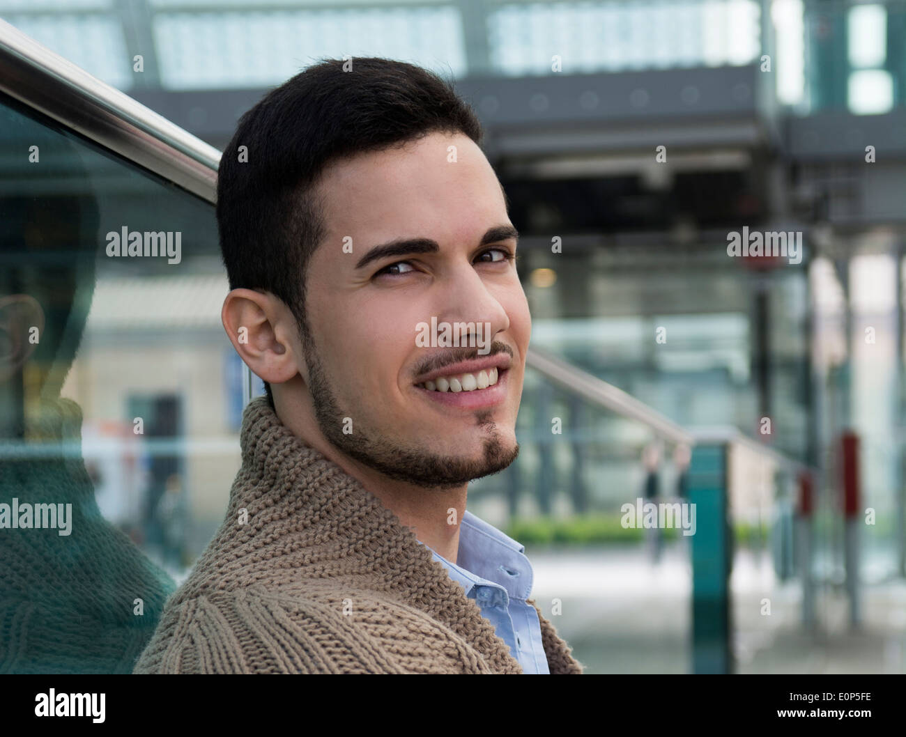 Hübscher junger Mann in öffentlichen Ort (Bahnhof, Flughafen) Lächeln in die Kamera Stockfoto