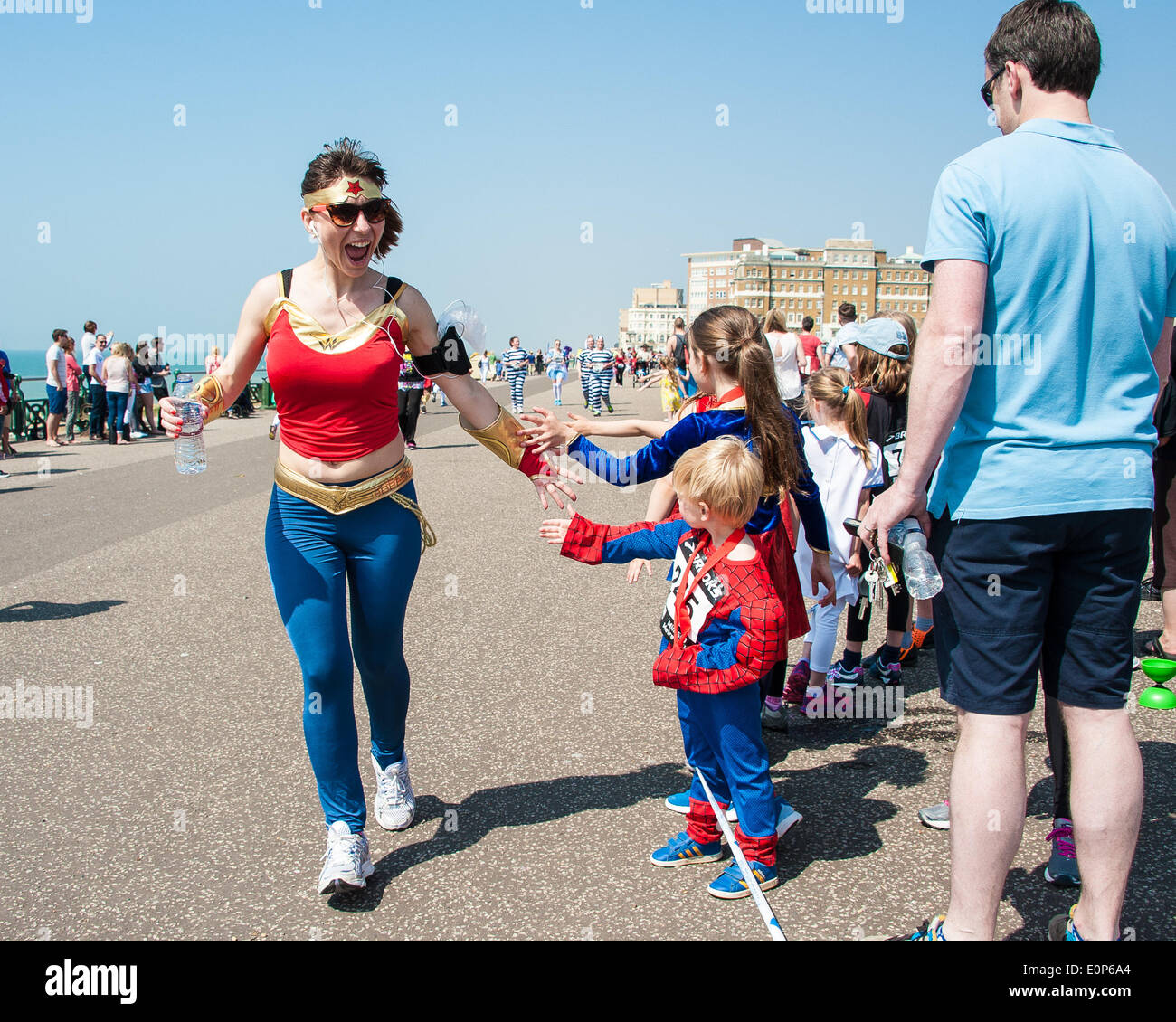 Brighton, UK. 18. Mai 2014. Läufer auf dem Abschlussball erhalten Unterstützung von der Masse in der Nächstenliebe Volkslauf an Hove Promenade zu Spenden für, übergeben sie an Afrika. Verkleidet als Helden oder Schurken, die sie in der Sonne - einige mehr ernst nehmen als andere entlang sprint. die Kinder Rennen einen 500metre Kurs, Erwachsene, 5K oder 10K. Bildnachweis: Julia Claxton/Alamy Live-Nachrichten Stockfoto