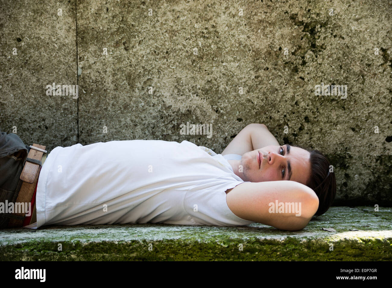 Hübscher junger Mann liegend auf Steinblöcken und Blick in die Kamera Stockfoto