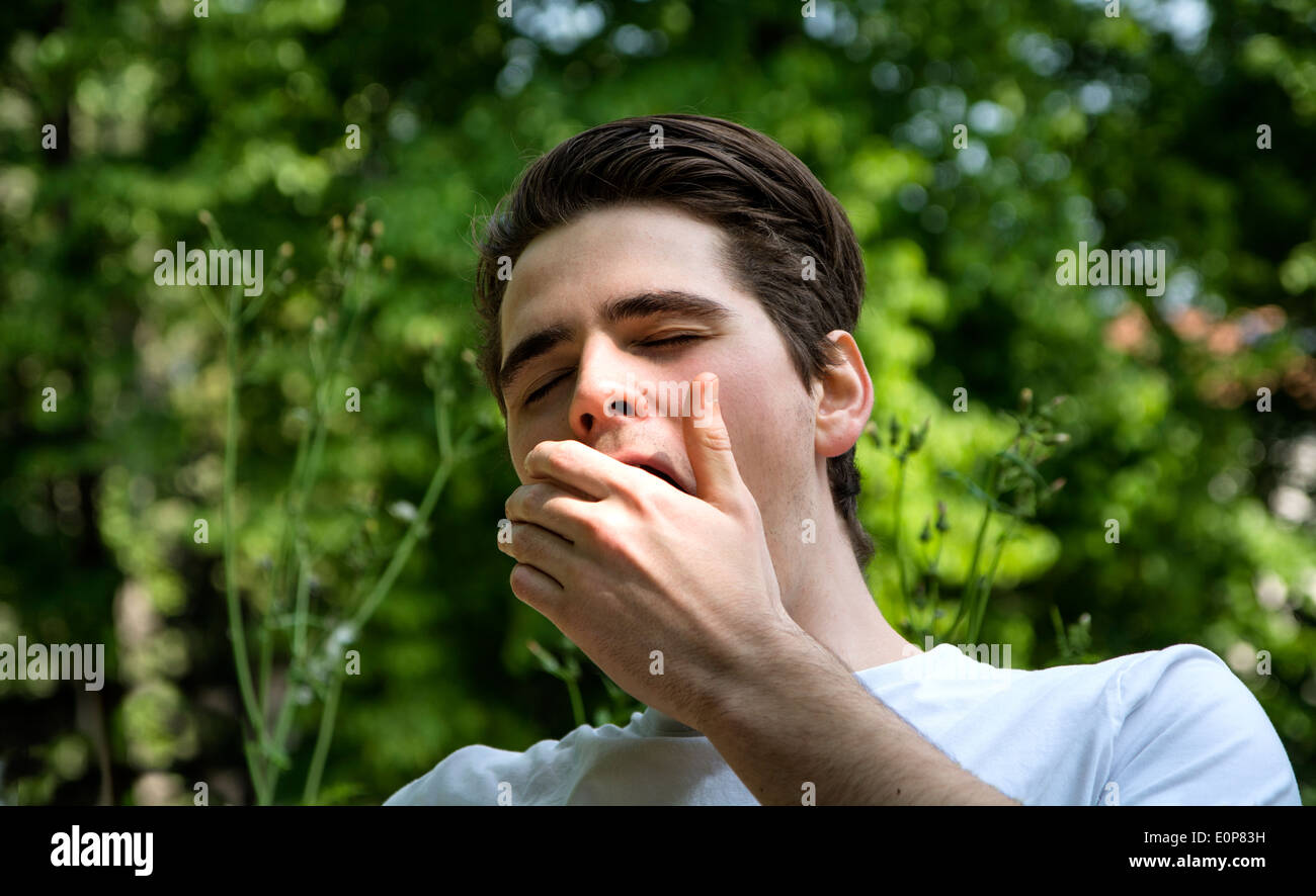 Müde oder gelangweilt junger Mann in einem Park, Gähnen, den Mund mit der hand Stockfoto